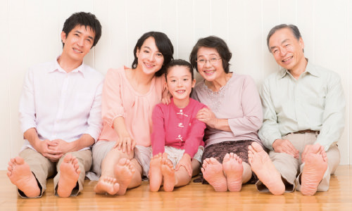 裸足でフローリングに座っている家族